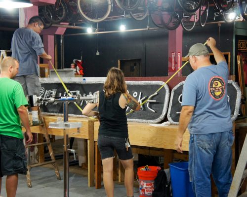 Volunteers hang the Brandon's Bike Shop sign.